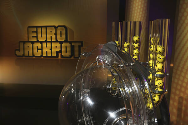 Ziehungsgerät mit gelben Eurojackpot-Kugeln und Eurojackpot-Logo im Hintergrund.