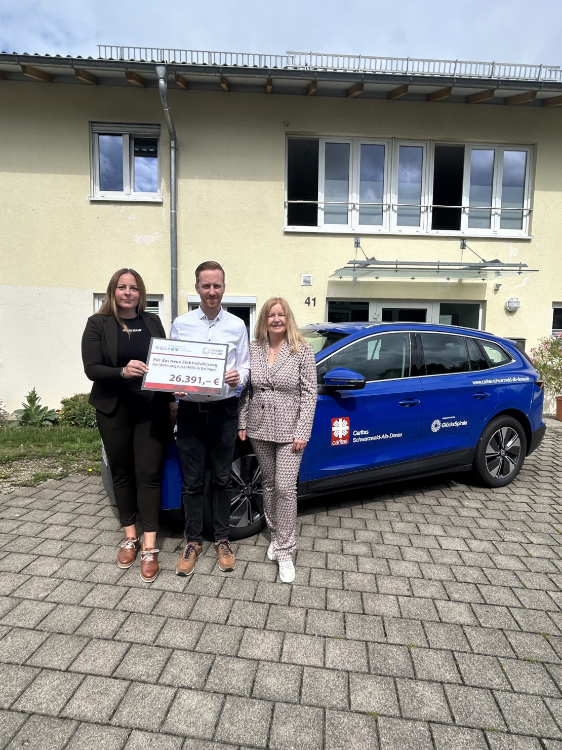 Regionaldirektorin Marina Roßmann übergibt den symbolischen Scheck für das Elektroauto an Johannes Geiger, Leiter Soziale Hilfen, und Monika Hipp, Stabsstelle Fundraising/Öffentlichkeitsarbeit, von der Caritas Schwarzwald-Alb-Donau.