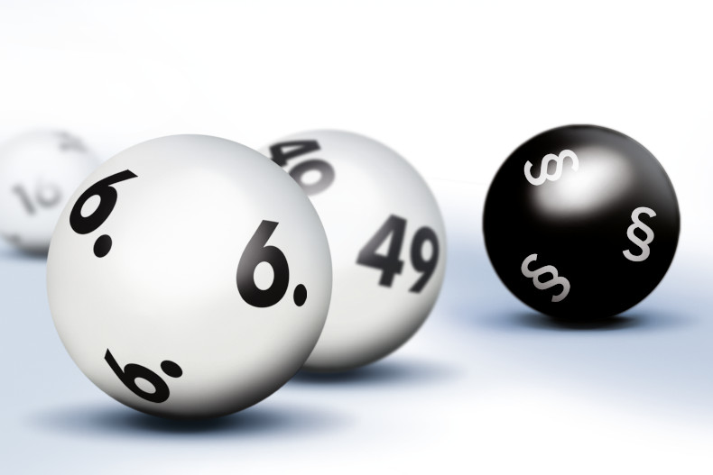 Drei weiße Lottokugeln mit den Zahlen 6, 49 und 16 und einer schwarzen Lottokugel, auf der das Paragrafenzeichen abgebildet ist.