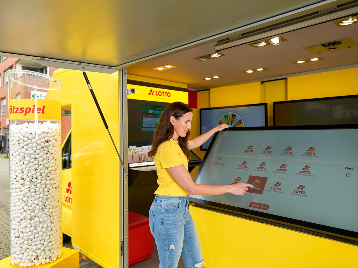 Eine junge Frau steht im Innenraum des Lotto-Mobils vor dem Gewinnspiel