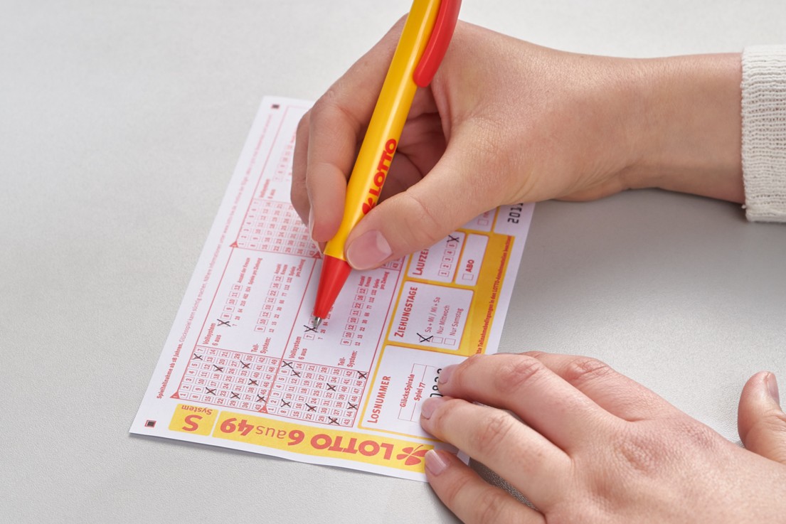 Hand setzt Kreuze auf Lotto 6aus49 Spielschein.