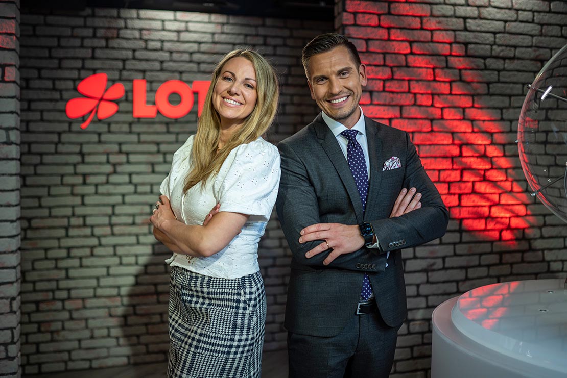 Lotto-Moderatorin Miriam Hannah und Moderator, Chris Fleischhauer stehen im Lotto-Studio und lächeln in die Kamera.