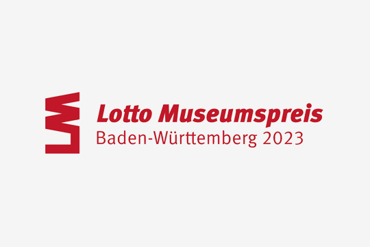 Lotto Museumspreis Baden-Württemberg 2023 in roter Schrift auf grauem Hintergrund.