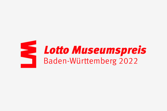 Lotto Museumspreis Baden-Württemberg 2022 in roter Schrift auf grauem Hintergrund.